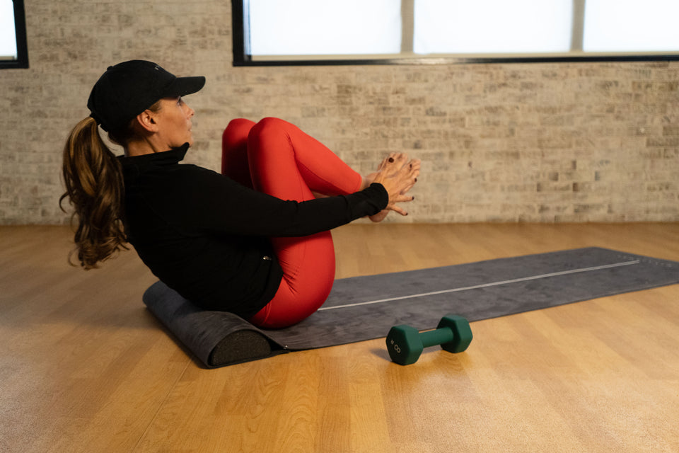 Natalie performing a crunch with the UTKATA CORE on the UTKATAMAT yoga mat, showcasing core strength, stability, and control.